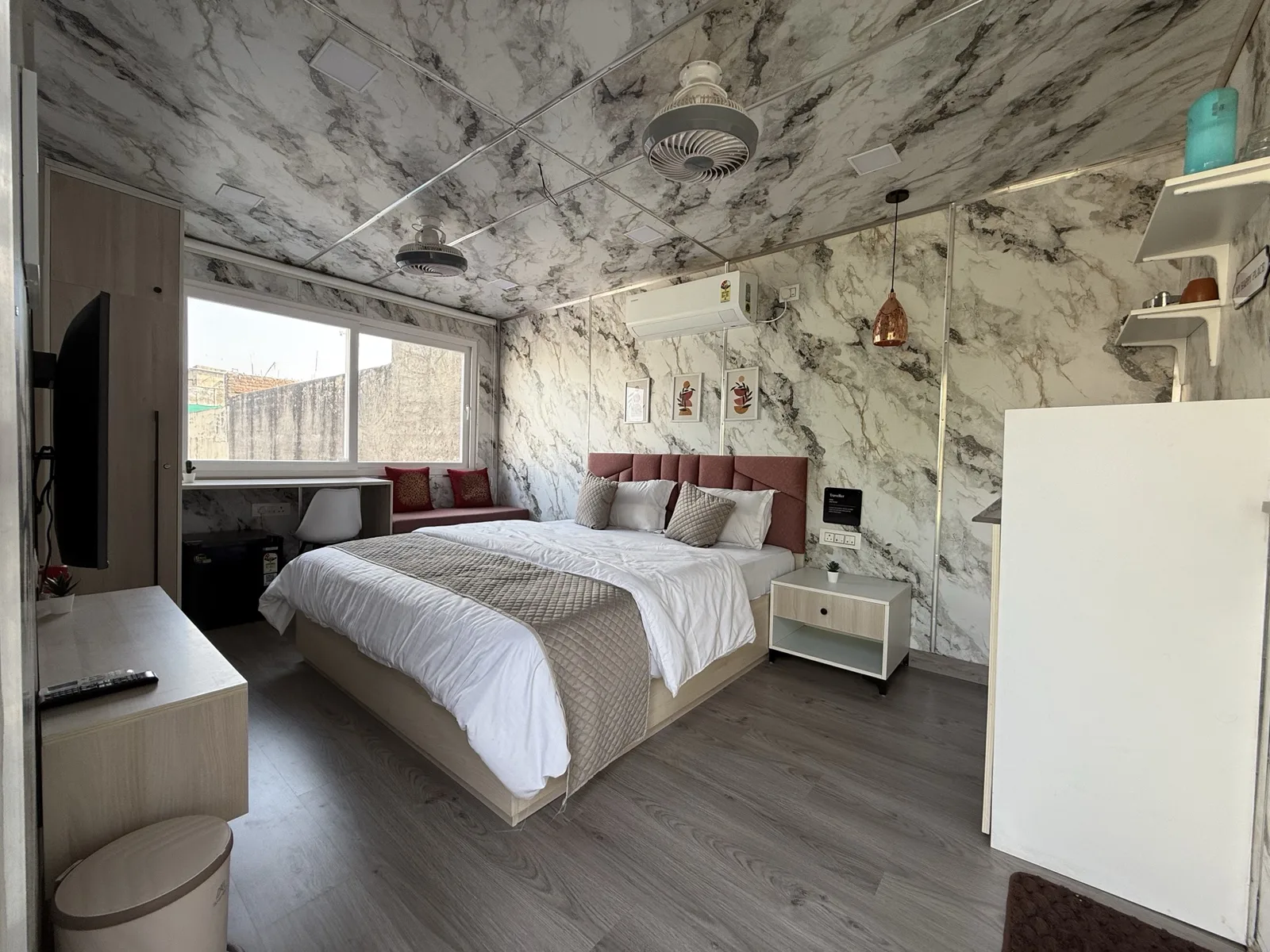 Bedroom with desk, TV and window inside a CabinWala container home