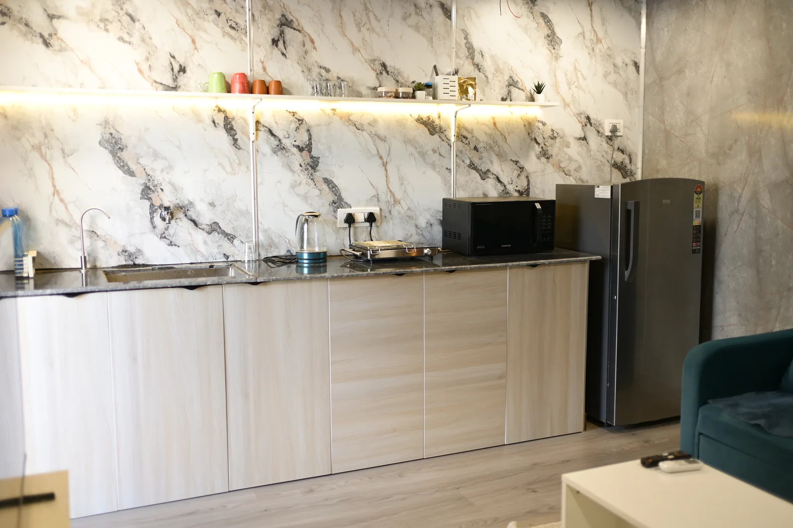 Kitchenette counter with marble backsplash, fridge and microwave inside the container Airbnb — CabinWala, Jaipur